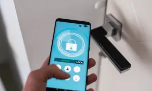Smartfon z aplikacją hotelową pokazuje, jak się zameldować w hotelu. Dotknij ikony zamka, by odblokować drzwi.