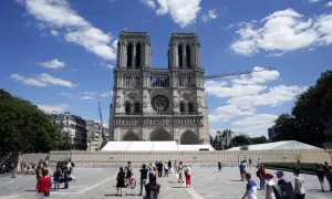 Katedra Notre Dame w Paryżu, otoczona placem z turystami i ogrodzeniem, wciąż budzi podziw, mimo trwającej odbudowy.