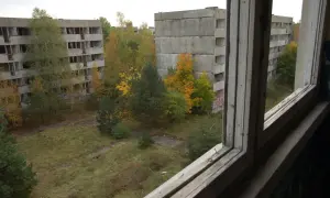 Pstrąże miasto widmo. Opuszczone bloki mieszkalne otoczone dziką przyrodą, zniszczone okna i puste balkony tworzą ponury krajobraz.