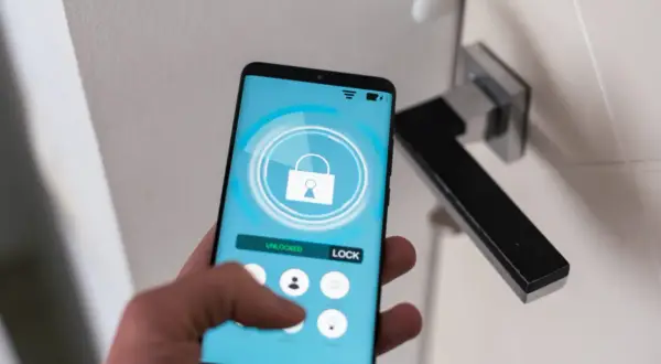 Smartfon z aplikacją hotelową pokazuje, jak się zameldować w hotelu. Dotknij ikony zamka, by odblokować drzwi.