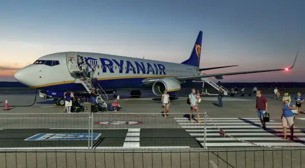 Ryanair przyloty Modlin: pasażerowie schodzą po schodkach z samolotu na płycie lotniska o zmierzchu.