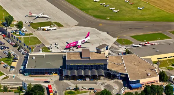 Lotnisko Wrocław na żywo: różowy samolot Wizz Air i mniejsze maszyny na płycie. Widać terminal i parkingi.