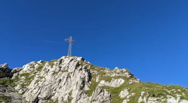 Giewont dla początkujących: szczyt z krzyżem i błękitne niebo. Widok na skaliste zbocze z trawą.