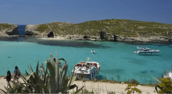 Malta co warto zobaczyć: Błękitna Laguna na Comino, z krystalicznie czystą wodą, łodziami i skalistymi klifami. Idealne miejsce na relaks.