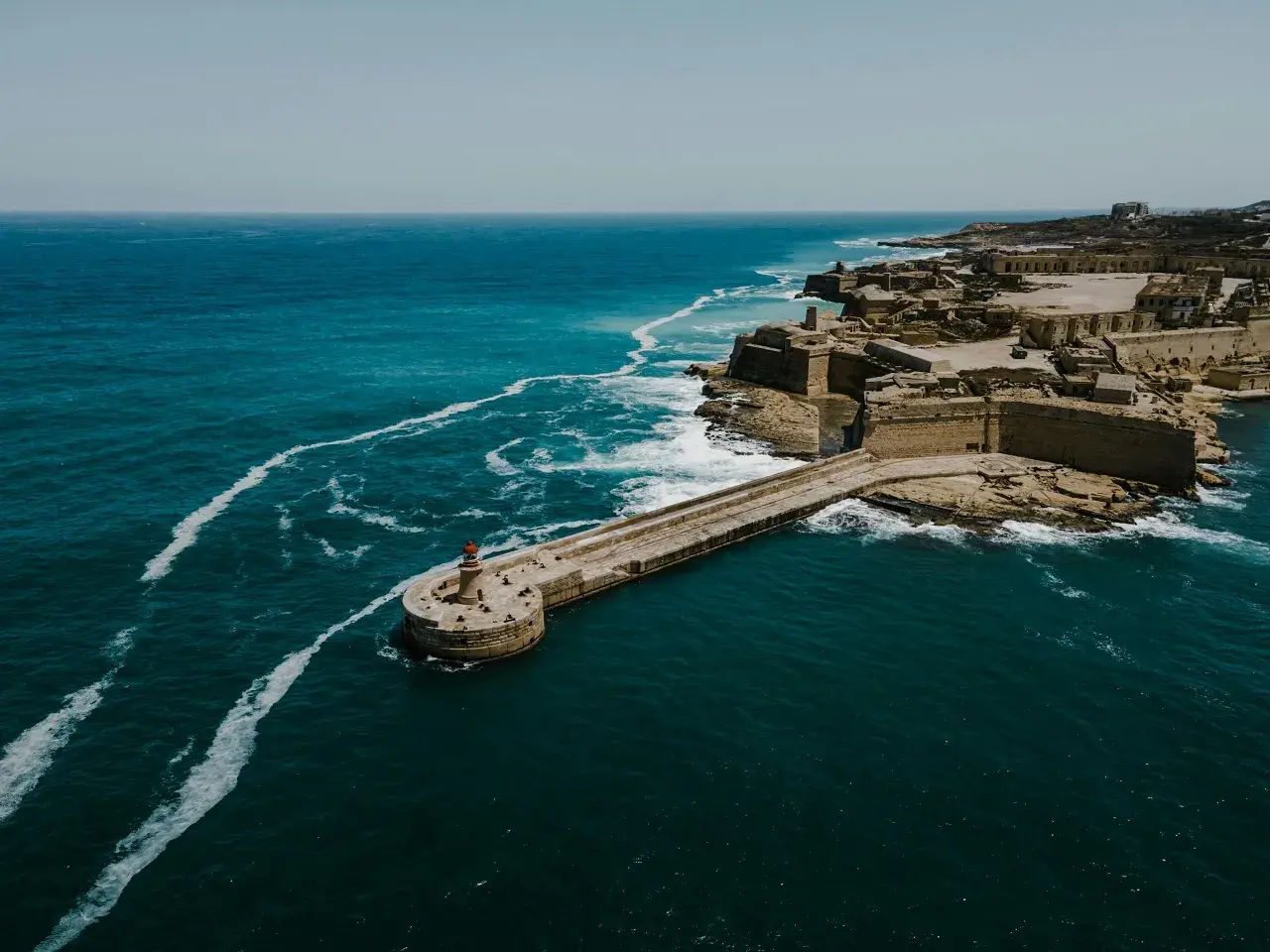 Malta, z latarnią morską i fortyfikacjami, zachęca do podróży. Ile trwa lot na Maltę z Polski? Krótko!