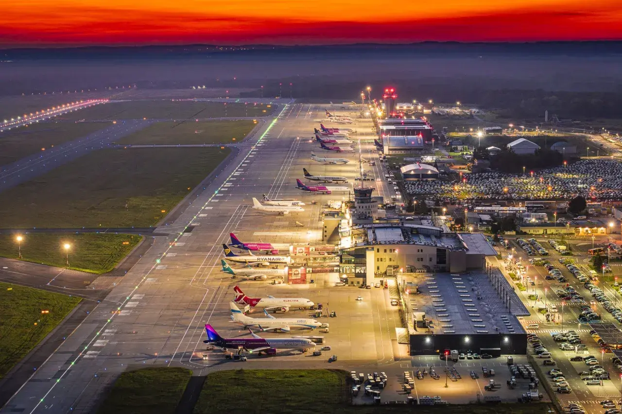 Lotnisko Katowice nocą, samoloty czekają na pasie startowym. Zastanawiasz się, ile trwa lot z Katowic do Marsa Alam?