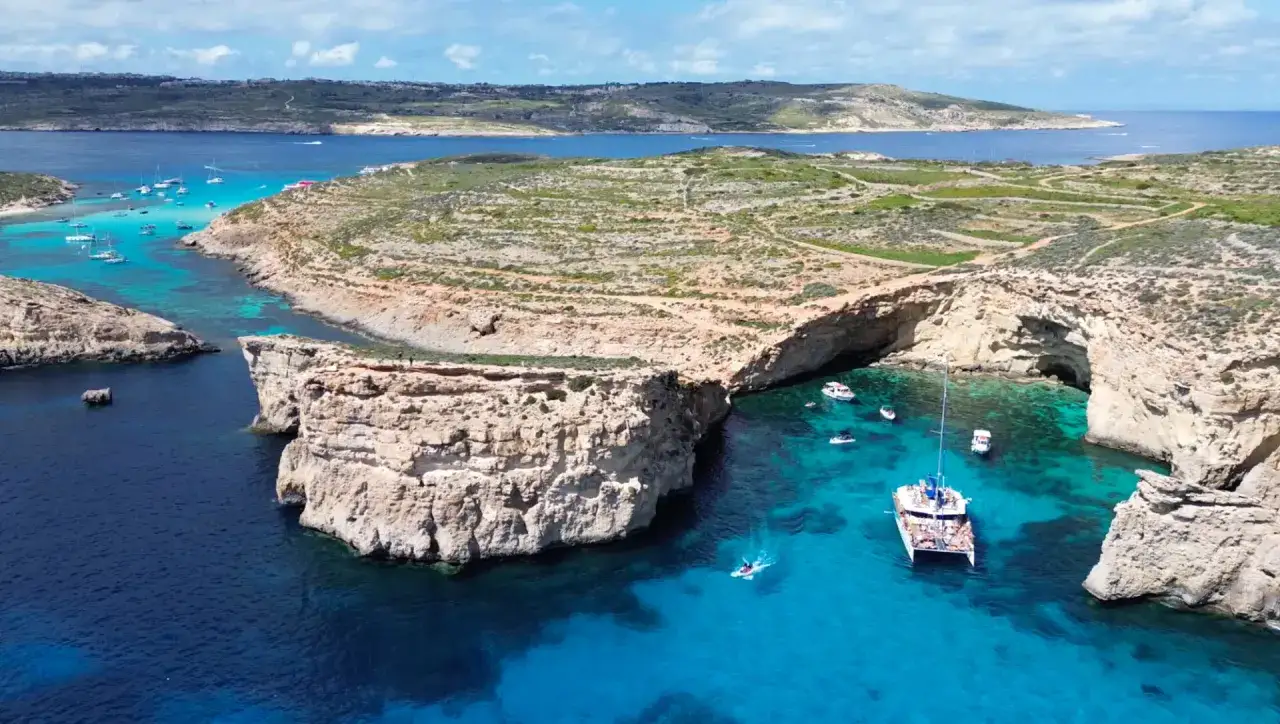Malta co warto zobaczyć: Błękitna Laguna na Comino, z jaskiniami i łodziami, to raj dla turystów.